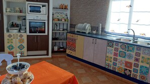 A kitchen with a tiled backsplash, a sink, and a window with a curtain.