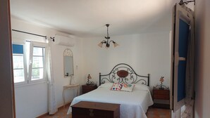 A bedroom with a bed, a dresser, a nightstand, a mirror, and a window.