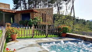 A stone building with a patio, outdoor seating, and a swimming pool.