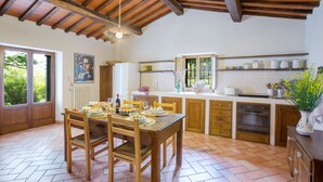 A kitchen with wooden cabinets, a dining table with chairs, and a hanging light fixture. - Belvedere House with panoramic views over the valley (Cortona)
