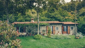 A rustic stone house with a tiled roof, surrounded by lush greenery and a well-maintained garden. - Belvedere House with panoramic views over the valley (Cortona)