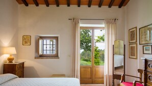 A bedroom with a bed, a nightstand, a chair, a dresser, and a window with curtains. - Belvedere House with panoramic views over the valley (Cortona)