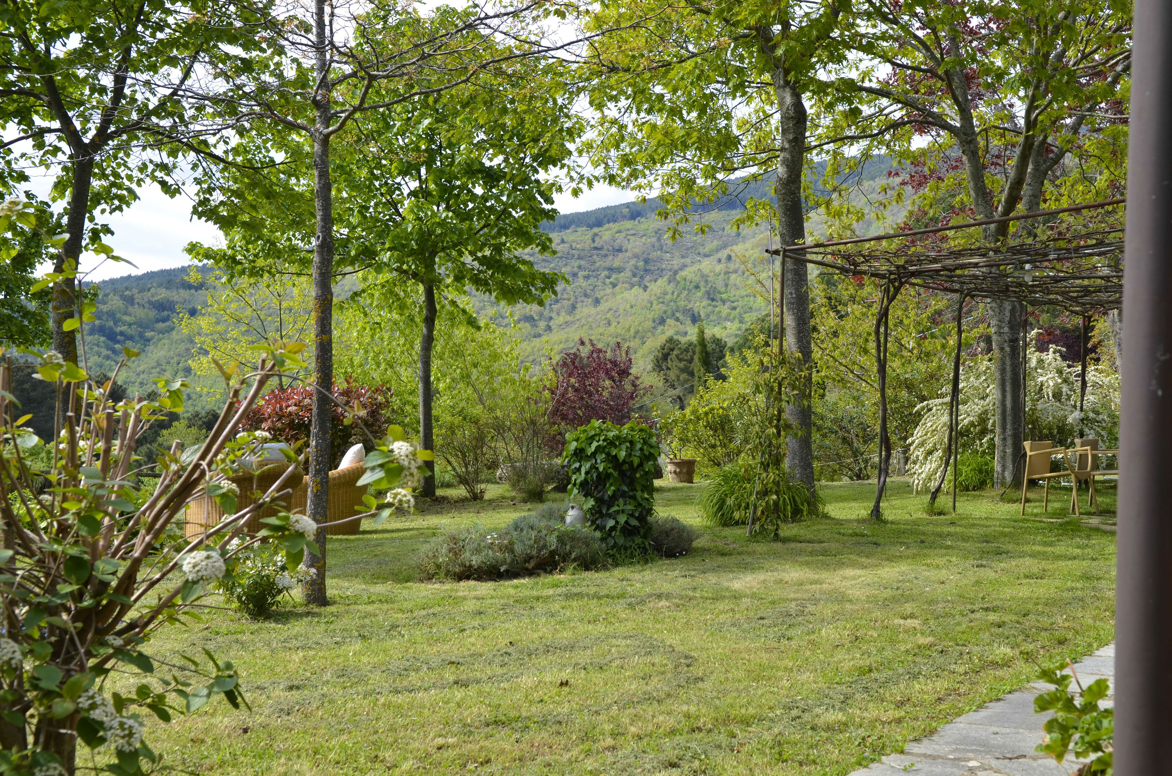 Un jardín con una pérgola, un banco y vistas a un paisaje montañoso.