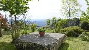 A stone bench with a potted plant in a natural setting with trees and a view of the landscape. - Belvedere House with panoramic views over the valley (Cortona)