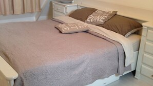 Un dormitorio con cama, almohadas, mesita de noche y cómoda.