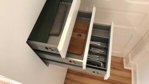 A kitchen with a built-in drawer unit, a wooden cutting board, and a countertop with a sink.