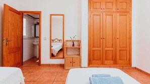 Ein Schlafzimmer mit einem Holzschrank, einem Spiegel, einem Nachttisch und einem Bett.