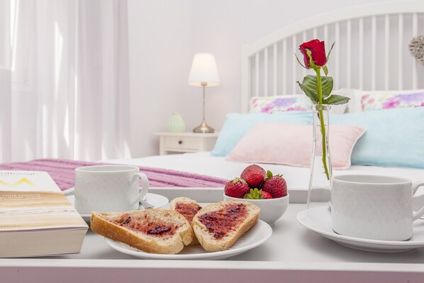 A neatly arranged breakfast table with toast, strawberries, a rose, and a book.