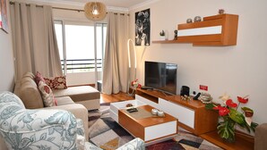 Una sala de estar moderna con un sofá, una mesa de centro, televisor y elementos decorativos.
