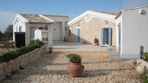 A courtyard with cobblestone flooring, a large terracotta pot, and a stone wall. - La Meridiana holiday home (Donnalucata ( Ragusa))