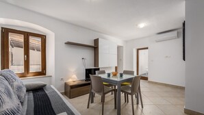 Una sala de estar moderna con un sofá, una mesa de comedor con sillas, un televisor y una lámpara.