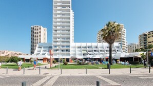 A modern building with multiple floors, a central open area, and a palm tree in the foreground. - Apartment Rocha | Sea View | Concorde Sky (Portimão)