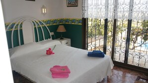 A neatly made bed with a white bedspread, a nightstand with a lamp, and a view of a balcony with a metal railing. - Minot house with sea and mountain views  (Dénia)