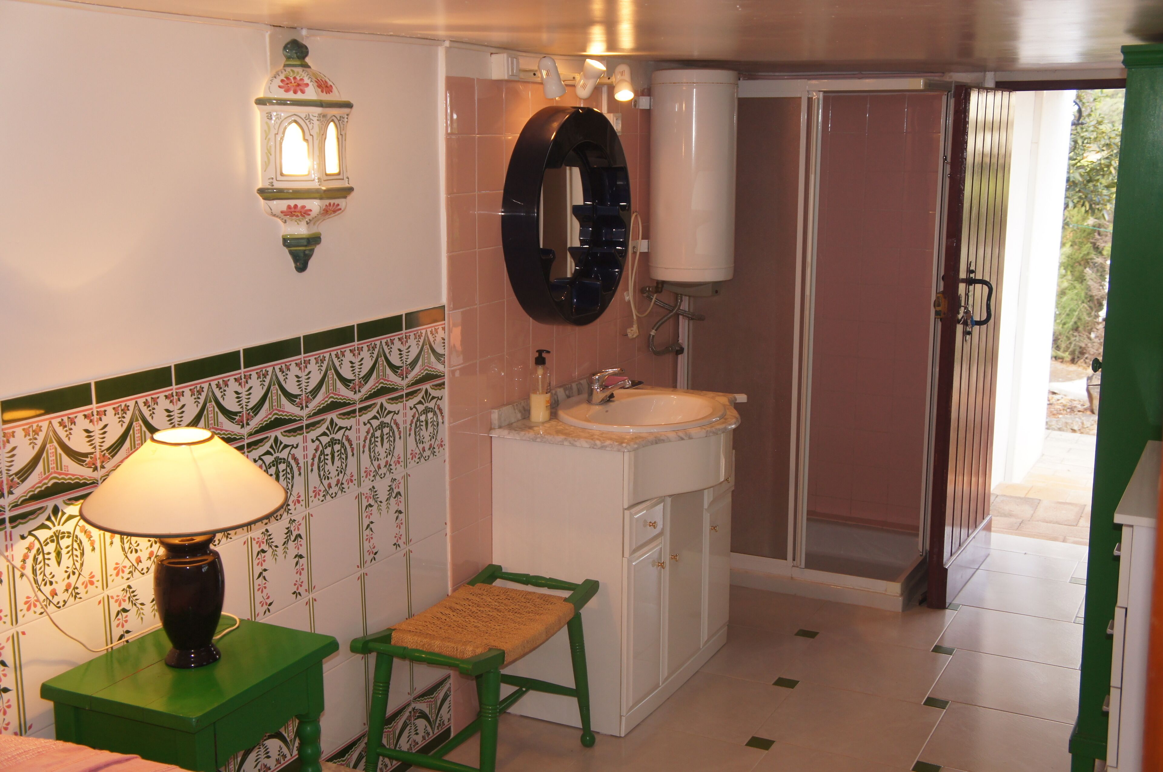 A bathroom with a sink, mirror, and a green chair.