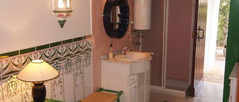 A bathroom with a sink, mirror, and a green chair.