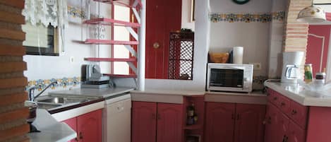 A kitchen with pink cabinets, a microwave, a coffee maker, and a sink.