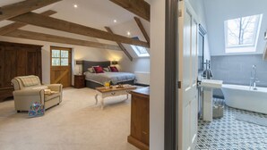A bedroom with a bed, bedside tables, a chair, and a small table with items on it. - Beautifuly restored Coach House & Granary set in the grounds of Glaneirw Mansion (Cardigan)