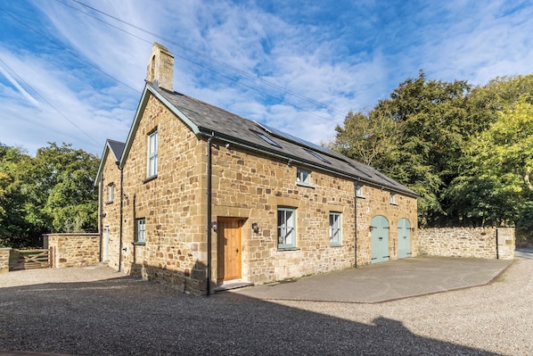 A stone building with a gabled roof, a wooden door, and two arched windows.