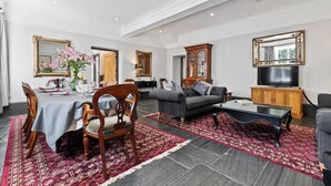 A living room with a dining table, chairs, a sofa, a TV, and a large mirror. - Beautifuly restored Coach House & Granary set in the grounds of Glaneirw Mansion (Cardigan)