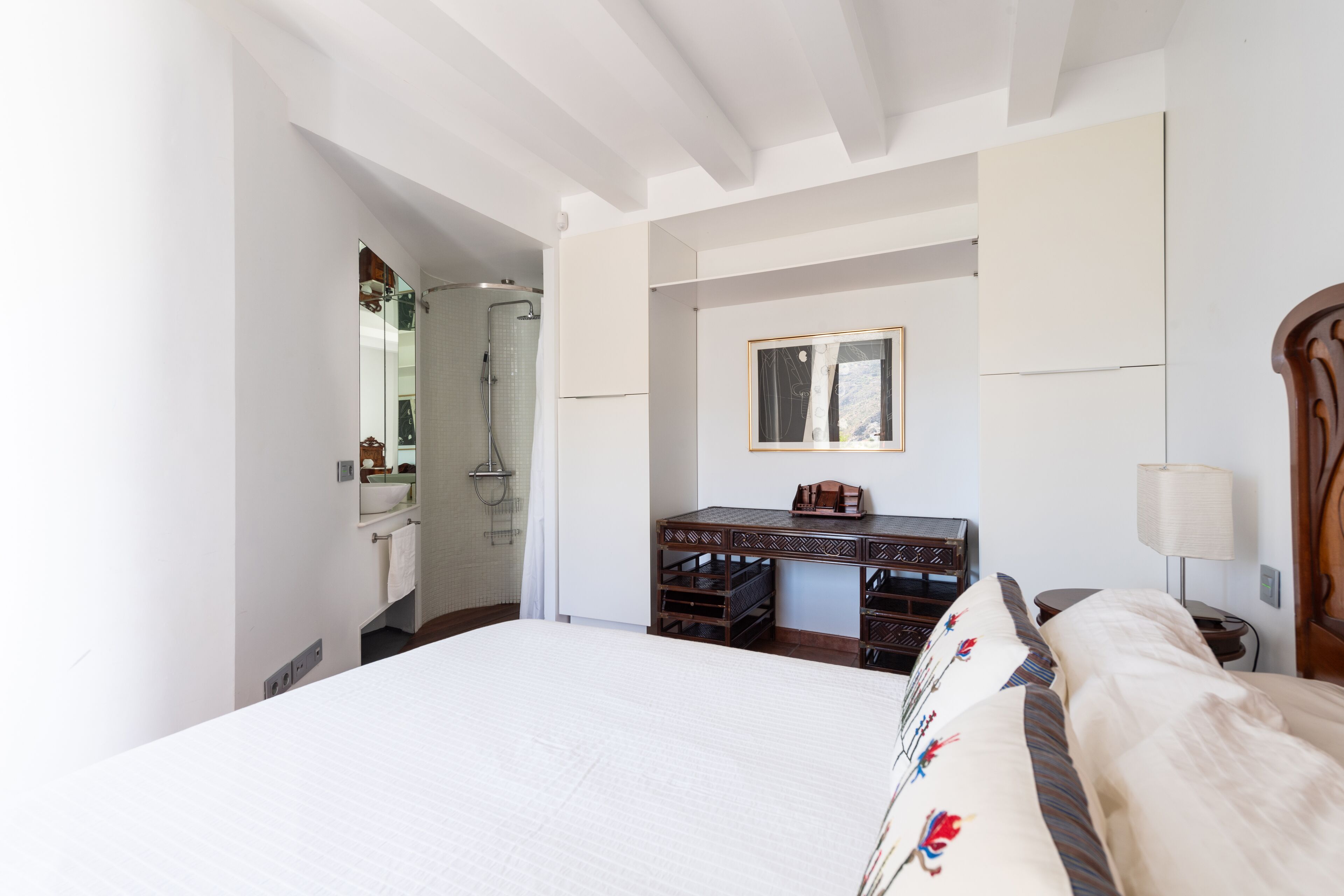 Une chambre d’hôtel avec un grand lit, un bureau en bois, un miroir et un espace douche.