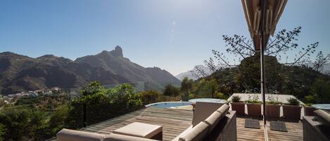 Terraza en la azotea con piscina, zona de descanso y vistas a la montaña.