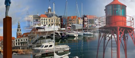 A marina with boats docked, a lighthouse, and a statue.
