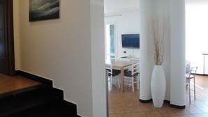 Un interior moderno con una escalera, un comedor y un televisor de pantalla plana.