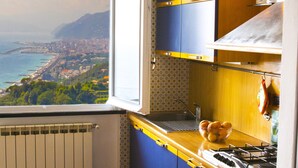 Una cocina con vista al mar, una ventana y un cuenco de fruta sobre la encimera.