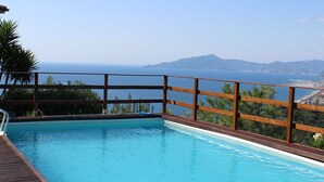 Una piscina con cubierta de madera y vista al mar y las montañas.