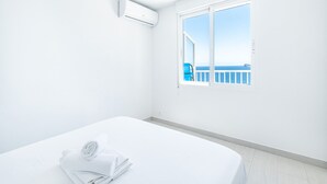 Habitación de hotel con cama, ventana y vista al mar, además de aire acondicionado.