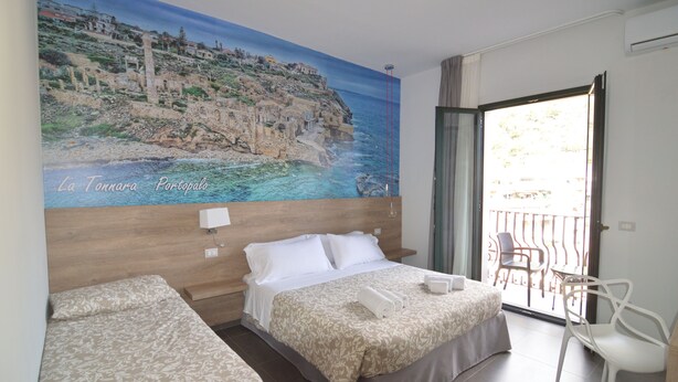 Una habitación de hotel con una cama, una silla y un balcón con vistas al mar.