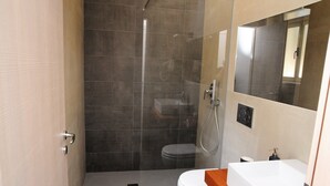 Un baño moderno con ducha de vidrio, inodoro y lavamanos con encimera de madera.