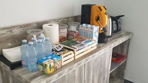 Una encimera de madera con diversos artículos, como botellas de agua, toallas de papel, una cafetera y productos envasados.