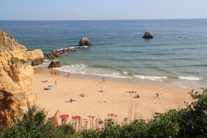 A beach with rocky cliffs, calm sea, and people sunbathing. - Dream Vacation in Praia da Rocha - T1 Sea View (Portimão)