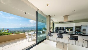 A modern kitchen with a large island, bar stools, and a view of the mountains. - VILLA HILLTOP (Nuestra Sra de Jesus)