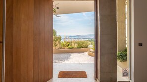 A modern interior with a wooden door leading to an outdoor patio with a view of the sea and hills. - VILLA HILLTOP (Nuestra Sra de Jesus)