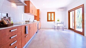 A modern kitchen with wooden cabinets, a stainless steel range hood, and a dining area with a table and chairs.