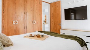 Une chambre à coucher avec un lit, une armoire en bois, une télévision et un plateau de petit-déjeuner posé sur le lit.