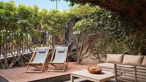 Une terrasse avec deux chaises longues, une table en bois et un canapé.