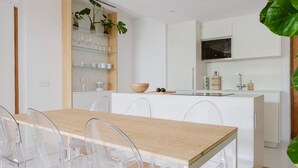 Une cuisine moderne avec des meubles blancs, un îlot central en bois et un four à micro-ondes encastré.