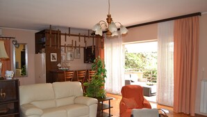 A living room with a sofa, armchair, coffee table, and a potted plant. - Pink apartment with two terraces, garden, a stone's throw from the beach (Umag)