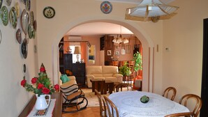 A dining area with a round table, chairs, and a vase of red roses. - Pink apartment with two terraces, garden, a stone's throw from the beach (Umag)