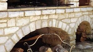 A stone fireplace with a metal log holder in front. - Pink apartment with two terraces, garden, a stone's throw from the beach (Umag)