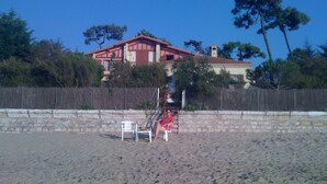 A beach with a red building in the background, a wooden fence, and a few trees. - Superb Basque villa. Direct access to the sea. 7 bedrooms including 4 doubles. 12/13 p (La Tremblade)