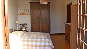 A bedroom with a wooden wardrobe, a bed with a checkered bedspread, a hanging coat rack, and a lamp. - Superb Basque villa. Direct access to the sea. 7 bedrooms including 4 doubles. 12/13 p (La Tremblade)