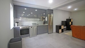 A modern kitchen with grey cabinets, stainless steel appliances, and a grey tiled floor. - House with private pool near Gerês (Terras de Bouro)