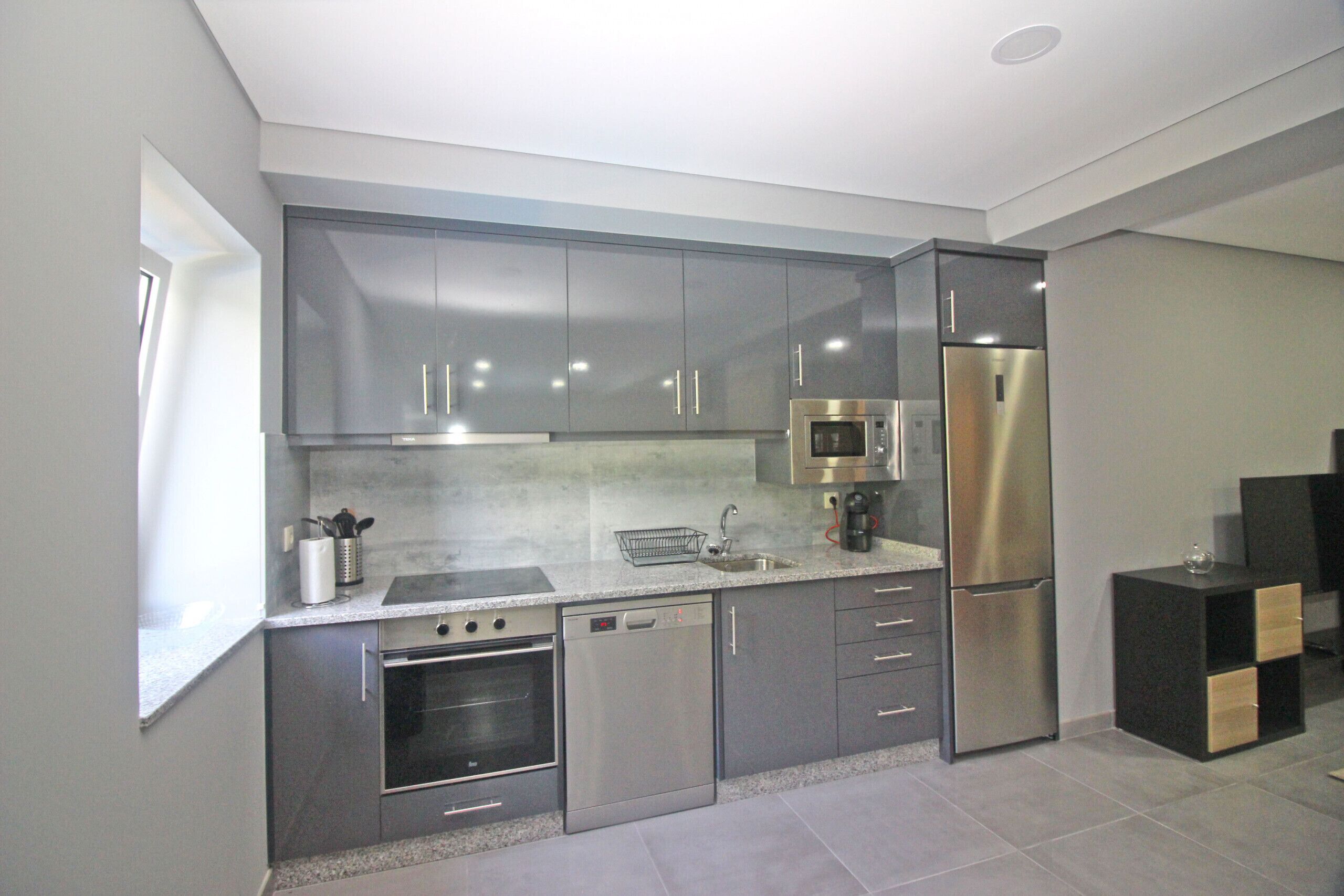 Una cocina moderna con electrodomésticos de acero inoxidable, armarios grises y un salpicadero de azulejos.
