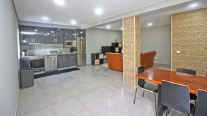 A modern kitchen with stainless steel appliances, a dining area with a wooden table and chairs, and a textured wall. - House with private pool near Gerês (Terras de Bouro)