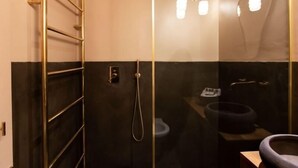 A modern bathroom with a glass shower enclosure, a black and gold vanity, and a towel rack.