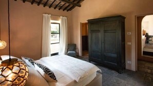 A bedroom with a bed, a wardrobe, a window with curtains, and a lamp.